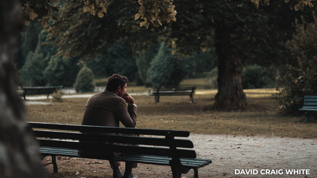 Person sitting alone on a park bench, reflecting quietly during burnout recovery.